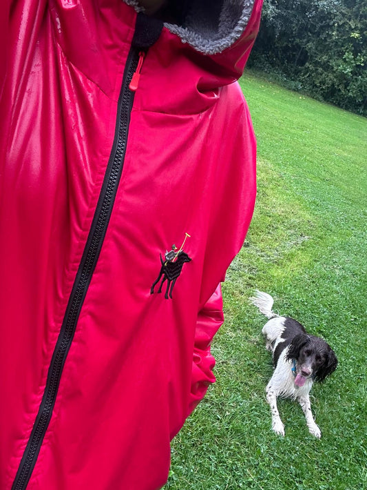 Woman wearing Poppy Red waterproof coat walking her dog in the rain