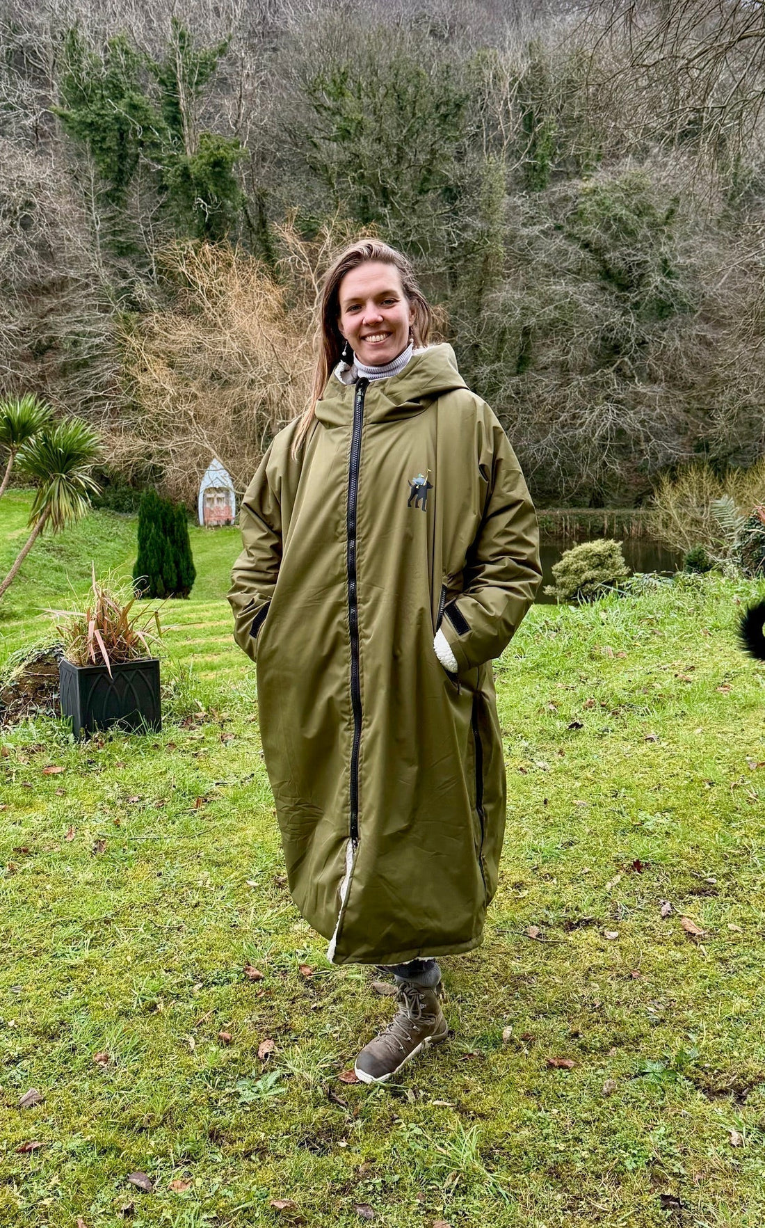 “Woman wearing the Hector & George long waterproof fleece-lined dog walking coat in the countryside on a rainy day.”